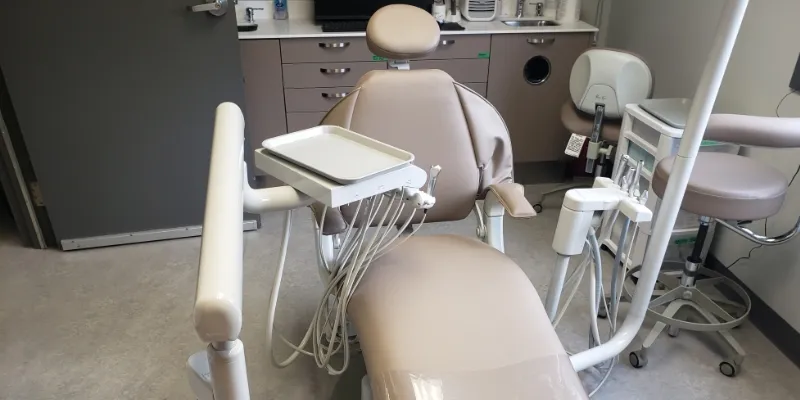 An empty dental chair and equipment in a treatment room.